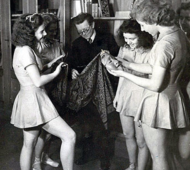 Februar 1943: Die letzte Aufnahme des Deutschen Tanzarchivs in Berlin vor dem Totalverlust bei einem britischen Luftangriff. Gestelltes Foto für eine offizielle Verwendung, Fritz Böhme zeigt den Tanzschülerinnen in der Bibliothek einen javanischen Sarong und eine japanische Maske.